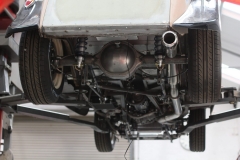 Lower view of the underside of the vehicle showing the rear axle and suspension system as well as the custom-built exhaust system.